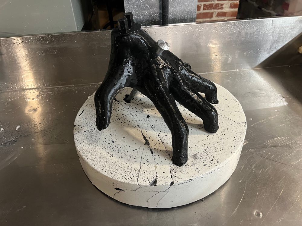 A black hand emerging out of stone it is bolted to