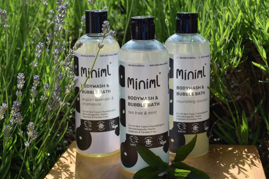 Three bottles of Miniml body wash next to a lavender plant 