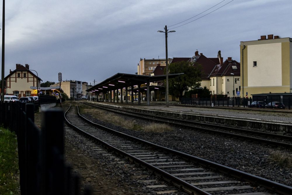 A railway station with 4 tracks, 1 island platform and 1 single-track platform, both platforms with large shelters spanning the whole width of the platforms, both with fluorescent lighting