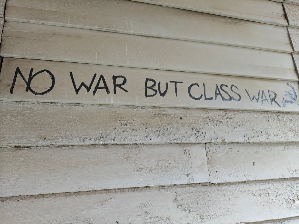 Old building side panel with NO WAE BUT CLASS WAR and the hammer and sicle communist symbol drawn after the sentence. 