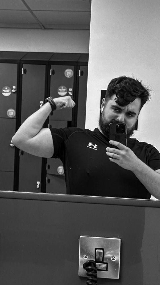 Oliver gym selfie, flexing in the mirror looking moody/annoyed for some reason
