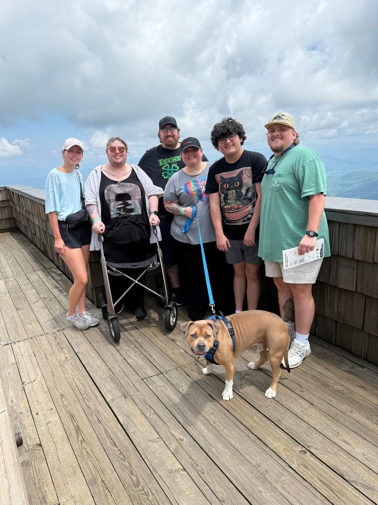 6 people and a brown dog pose at the top of Brasstown Bald.
