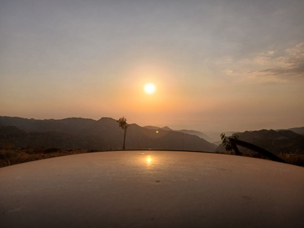 The sun close to dawning over mountains and a car roof