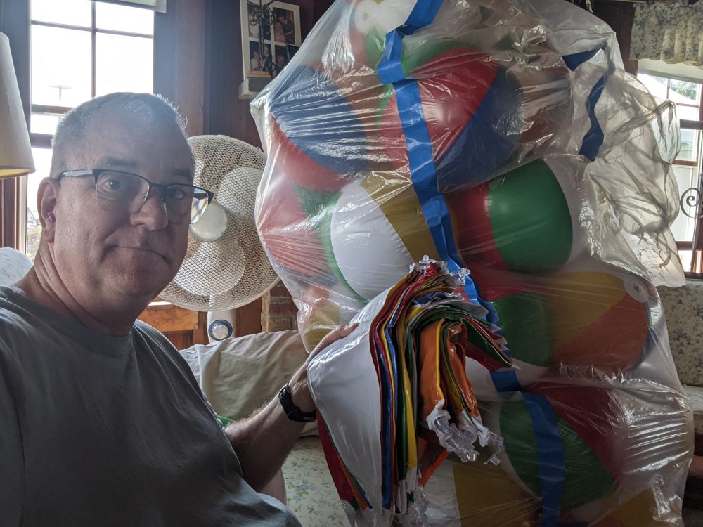 Me with a huge bag of inflated beach balls and a stack of uninflated ones in my hand.