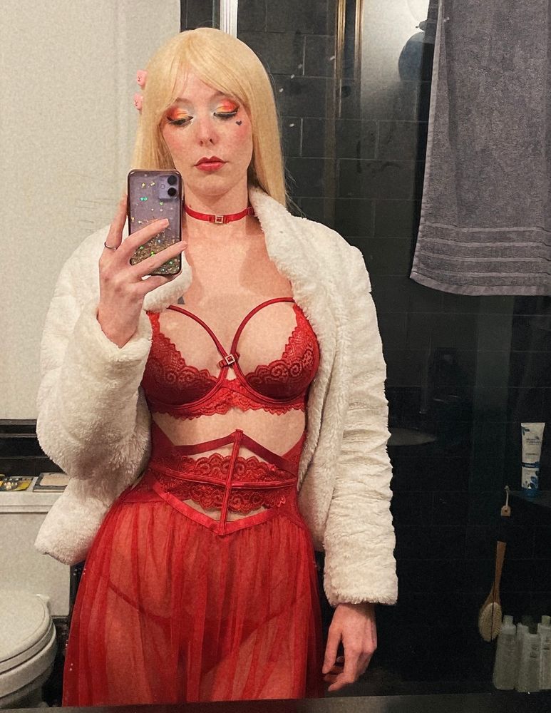 Blonde white girl in colorful makeup, a white fur coat, and red lingerie.
