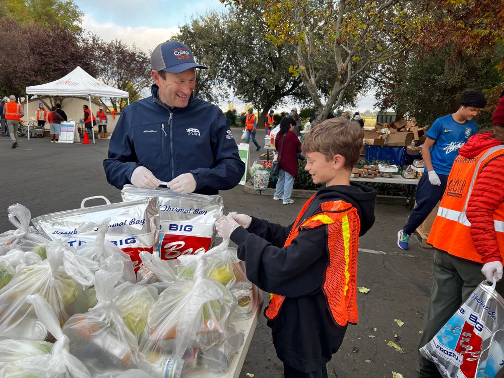 A photo of Josh Friday and a young boy preparing food to be handed out at a food distribution event at YOLO Food Bank.