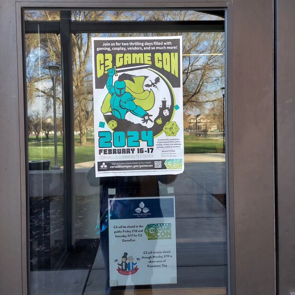 A photo of a window at the Corvallis Community Center in Oregon with promotional posters for an event called C3 GameCon coming up between February 16-17th of 2024.