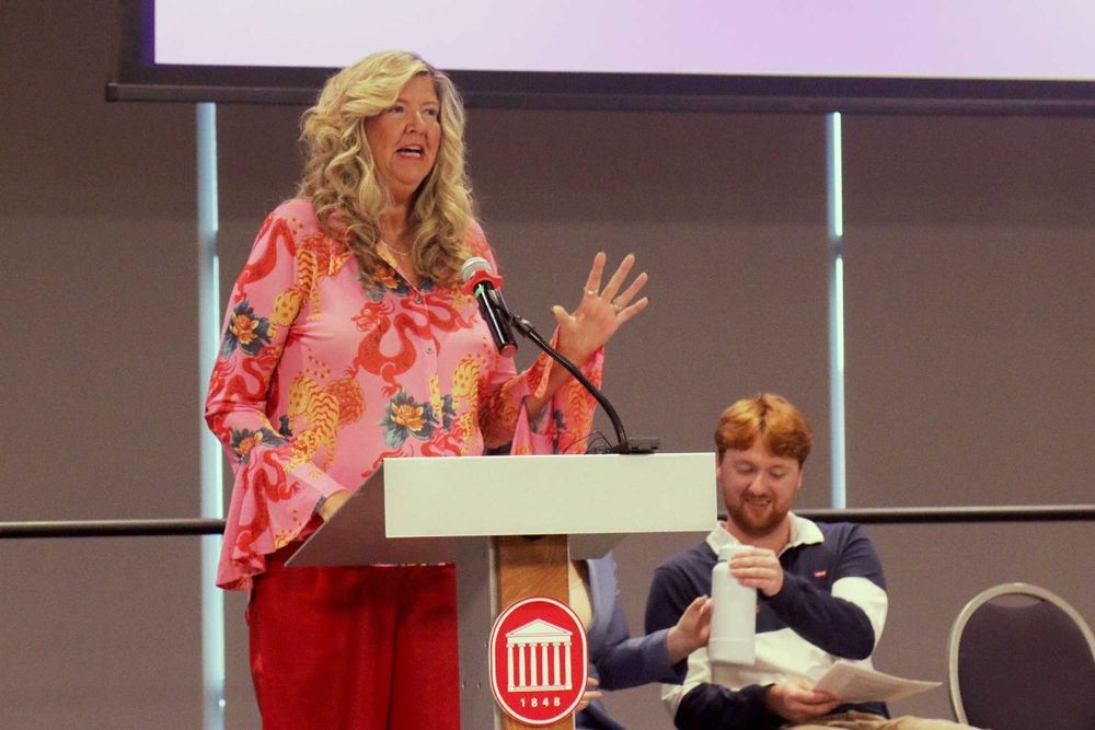 Gloria johnson stands at a lectern speaking 