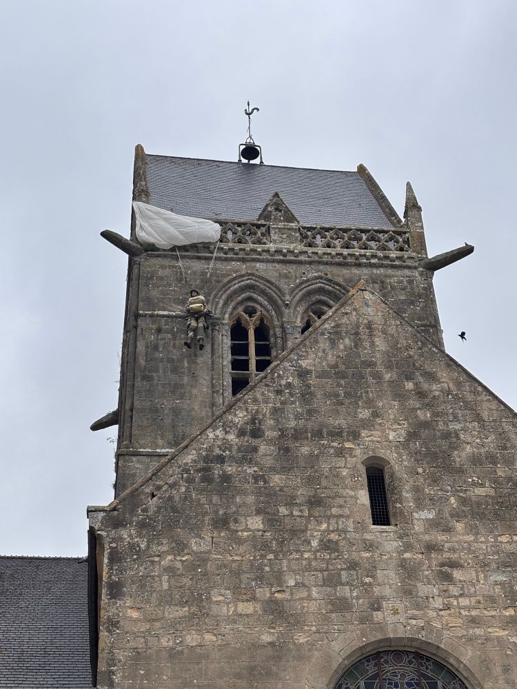 Kirche von Saint-Mère-Église mit symbolhaft daran hängender Fallschirmspringer-Figur