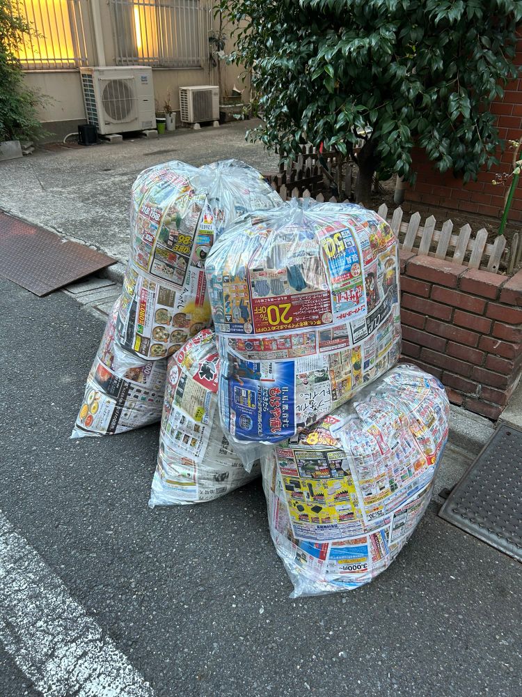 Clear bags of trash on the street in Tokyo with liners made from colorful newspaper ads so you can’t see the trash inside. 