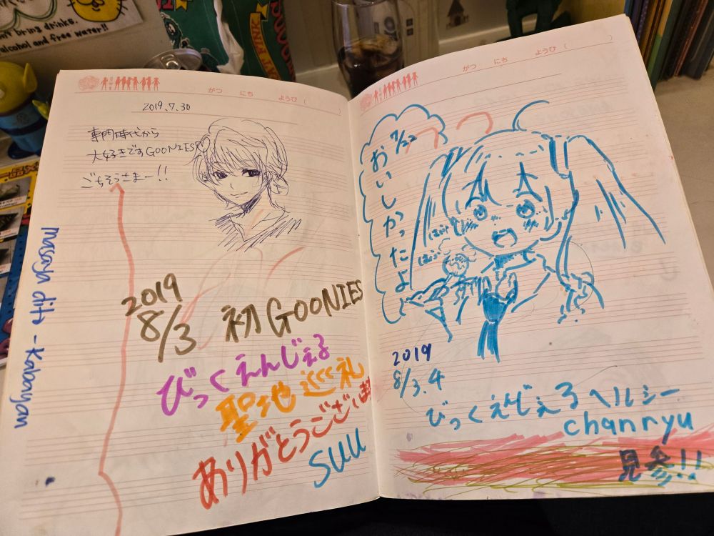 A notebook that guests have left messages in, with some anime doodles. One page is Miku eating takoyaki