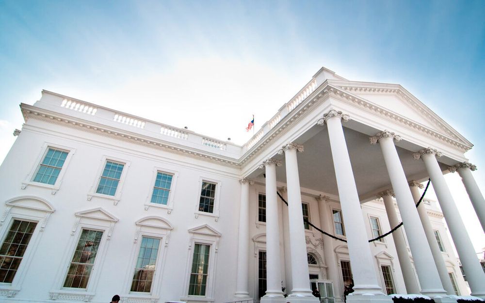 A low-angle view of the White House, in bright sunlight.