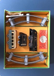 Train mécanique JEP, dans sa boite d'origine, comprenant une loco à vapeur aérodynamique, son tender et un wagon, des rails courbes ainsi que la fiche de garantie de sortie d’usine datée  01 02 1956 et la notice d’utilisation.