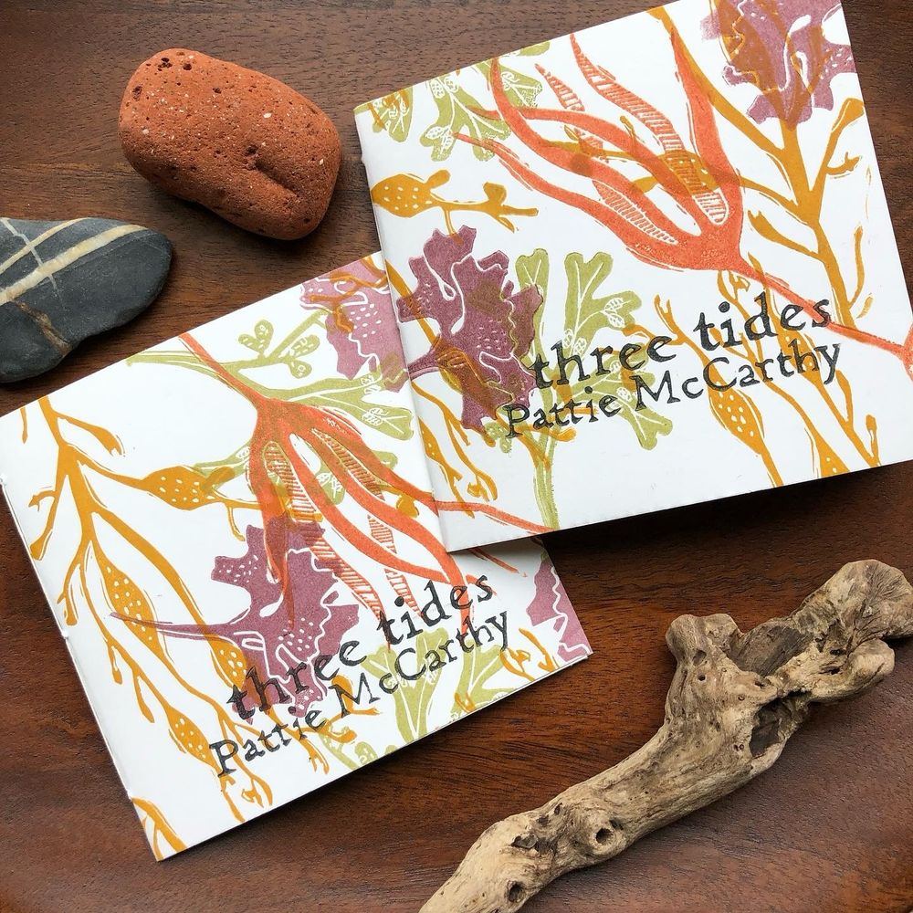 Two copies of a small poetry chapbook with linocut covers in a multicolored seaweed pattern. The title is “three tides” by Pattie McCarthy. Design © Shanna Compton for Bloof Books, 2022.