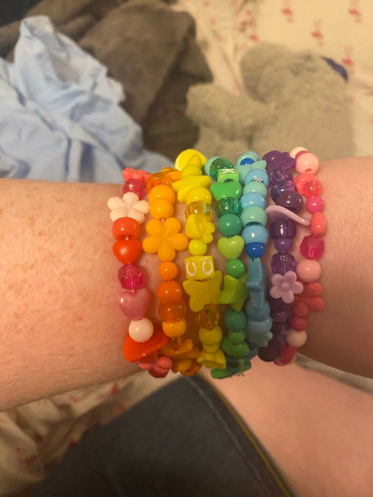 White arm wearing a rainbow of monochrome bracelets