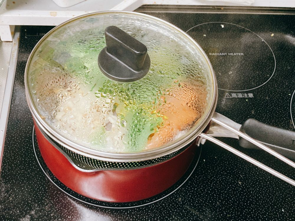 片手鍋にザルを乗せて野菜や肉を蒸している