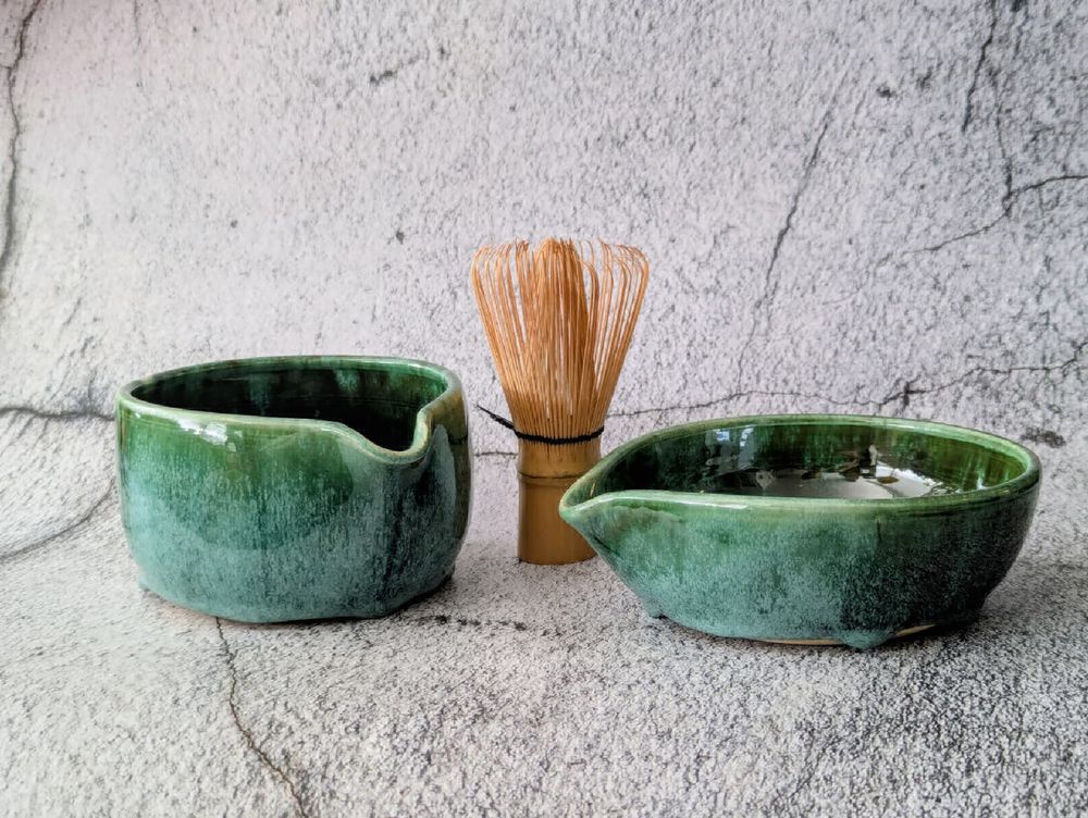 Two green glazed matcha bowls with whisk
