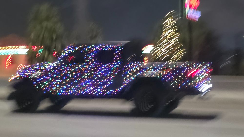 And pick up truck completely covered in Christmas lights with a lit Christmas tree in the bed of the truck.