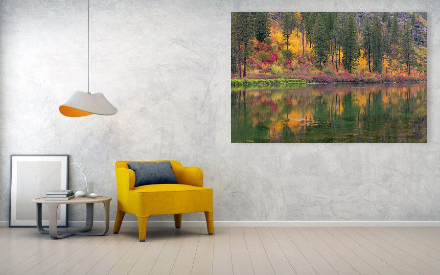 A modern living room features a vibrant yellow chair with a dark cushion, a minimalist side table with decor, and a large framed landscape art piece. The art shows a serene river reflecting autumnal trees, evoking calm and warmth.
Canvas Prints are 50% off at certain sizes for a limited time with this autumnal image. 