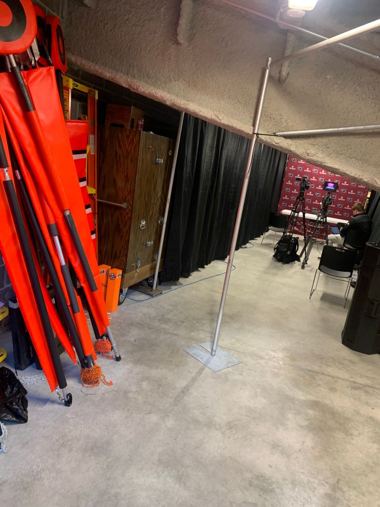 Storage closet with extra down makers, pylons and a table set up for a press conference. 