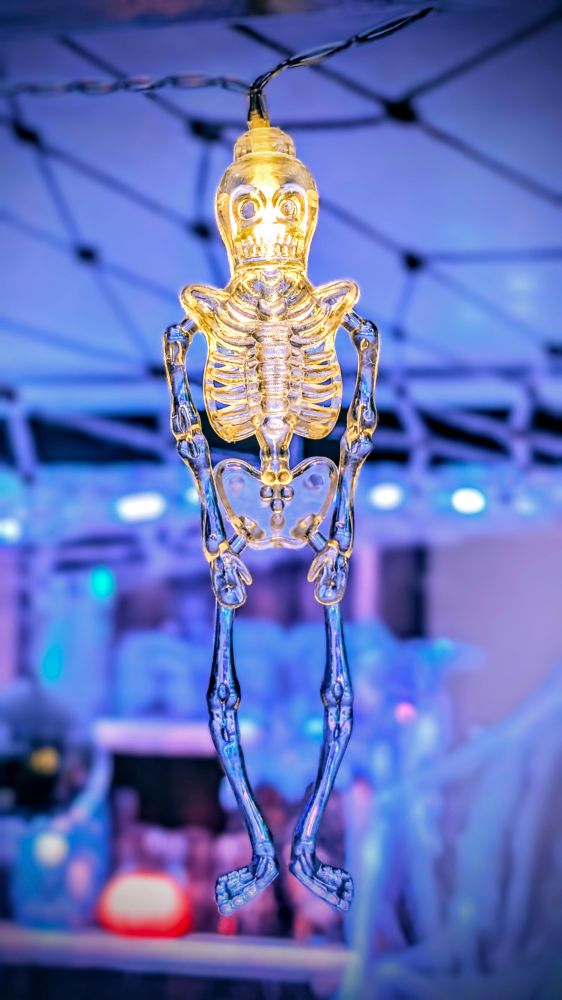 Ein Teil einer Lichterkette, in der die einzelnen Leuchtelemente als Skelette mit einer kleinen LED im Kopf ausgestaltet sind. 