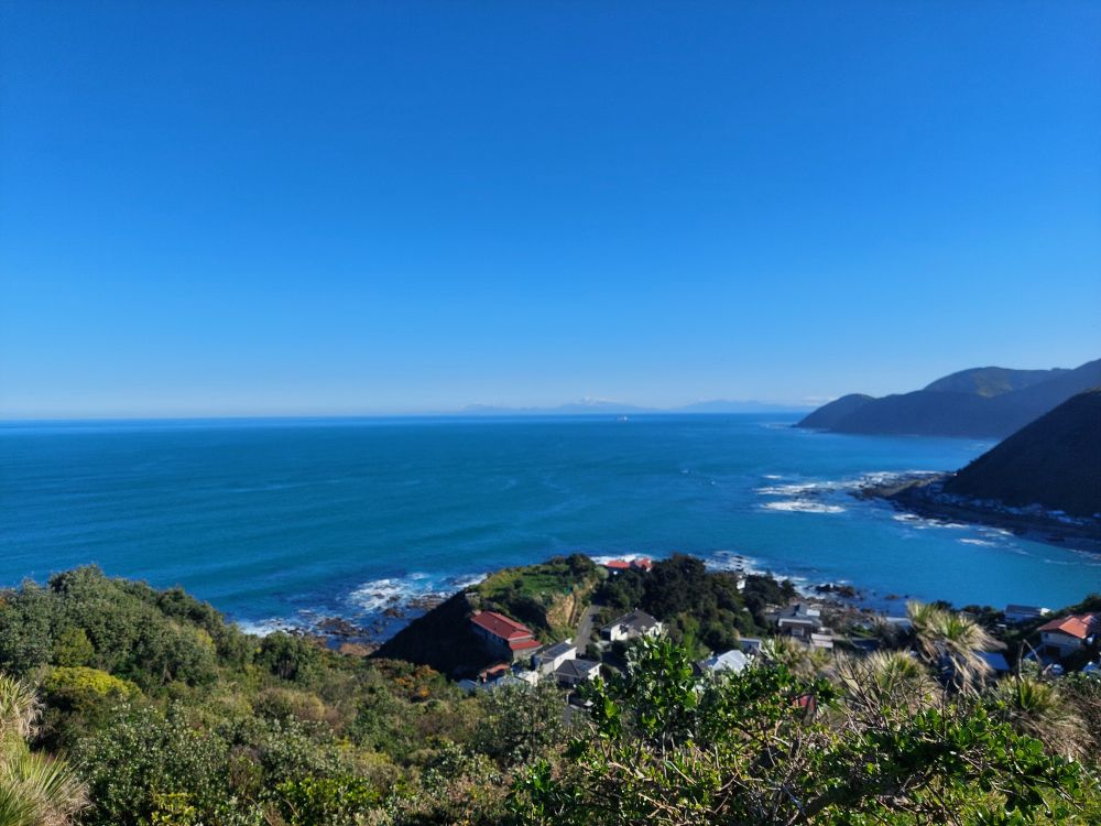 Photo looking over Ōwhiro Bay and towards the cook strait. In the distance you can see the snow topped kaikouras of the South Island