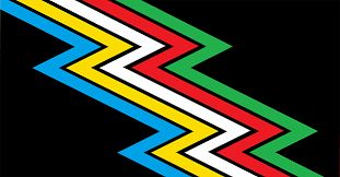 Primer diseño de la bandera del orgullo de la discapacidad. Bandera con fondo negro y un rayo en zigzag que cruza diagonalmente de la esquina superior izquierda a la esquina inferior derecha. El rayo está compuesto por varias franjas de colores: azul, amarillo, blanco, rojo y verde, cada una bordeando a la otra. Esta bandera es conocida como la bandera de la discapacidad, que representa la diversidad y la inclusión de las personas con discapacidad.