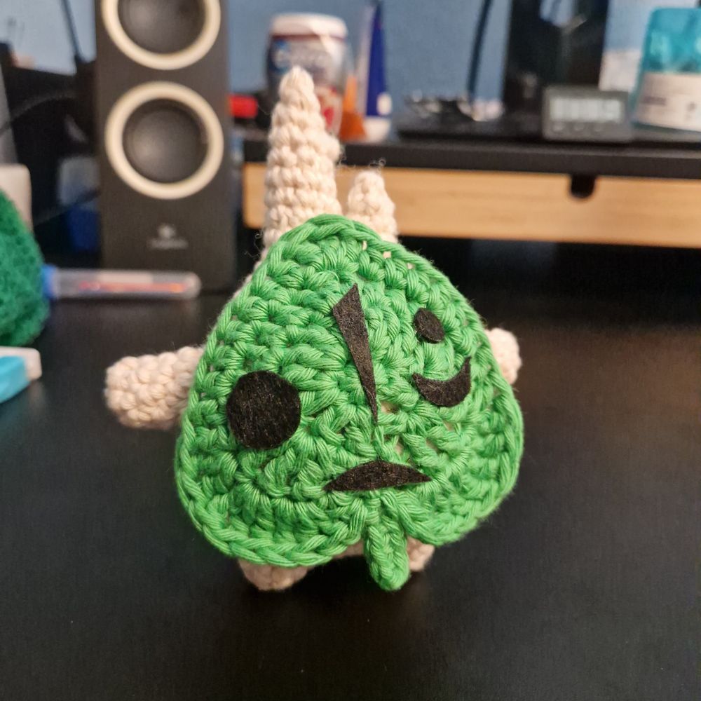 A crocheted plush of Makar from wind waker. Makar is a forest fairy that wears a leaf as a mask on his face. The plush is about 12 cm tall.