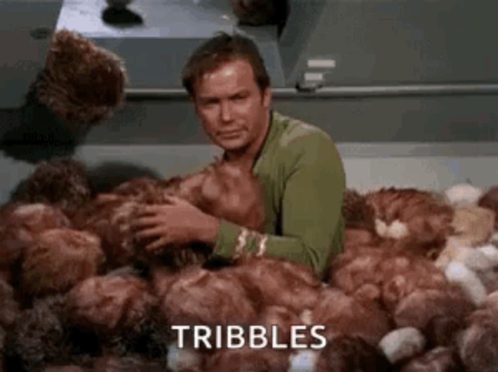 a man is sitting in a pile of chickens and says tribbles .