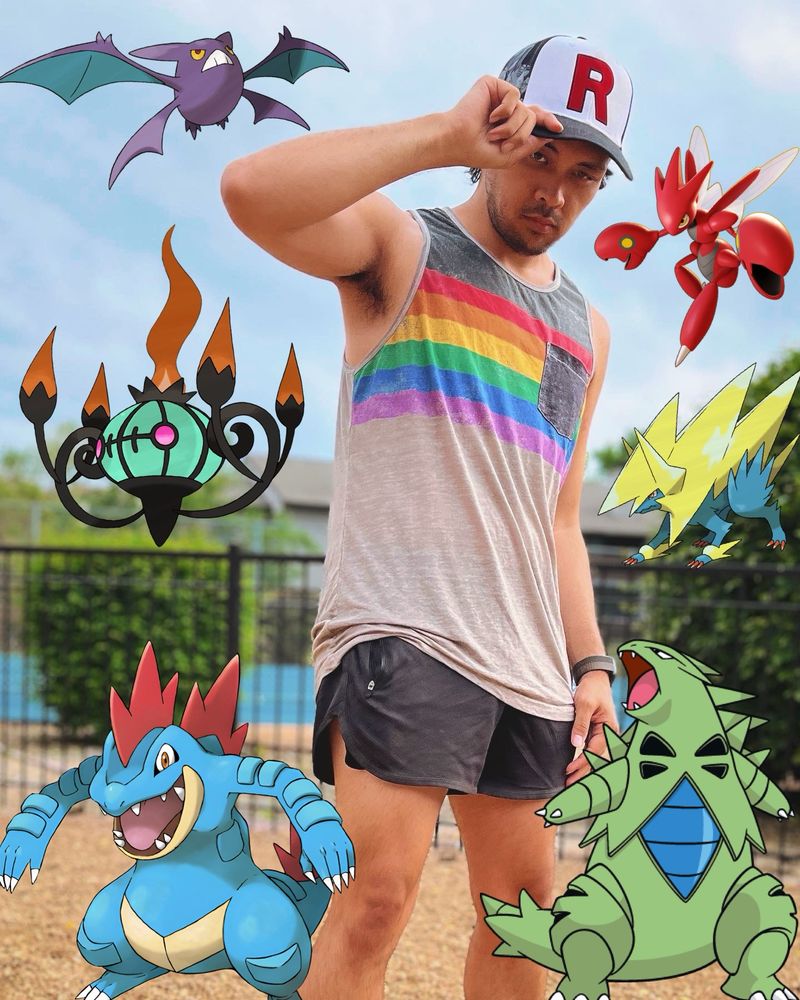 Me with a Pride tank top and a Team Rocket cap, accompanied by some black short shorts.

I am surrounded by Pokemon of all the colors of the Pride flag.

Pokemon starting from the top right and going clockwise: Scizor, Mega Manectric, Tyranitar, Feraligatr, Shiny Chandelure, and Crobat