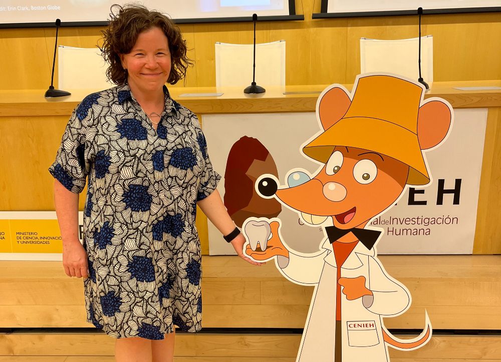 Erin Dunn standing beside a large print-out of the Ratón Pérez character