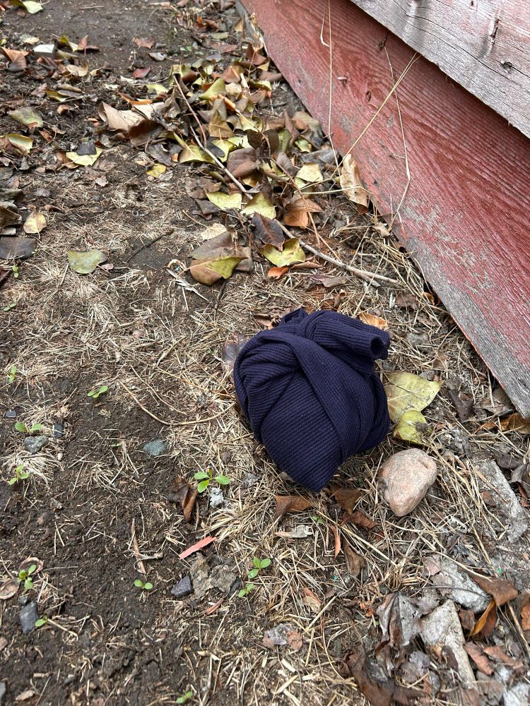 A long sleeved navy waffle shirt is tied neatly around a very full bag of liquid. So full, that it bounces a little. 