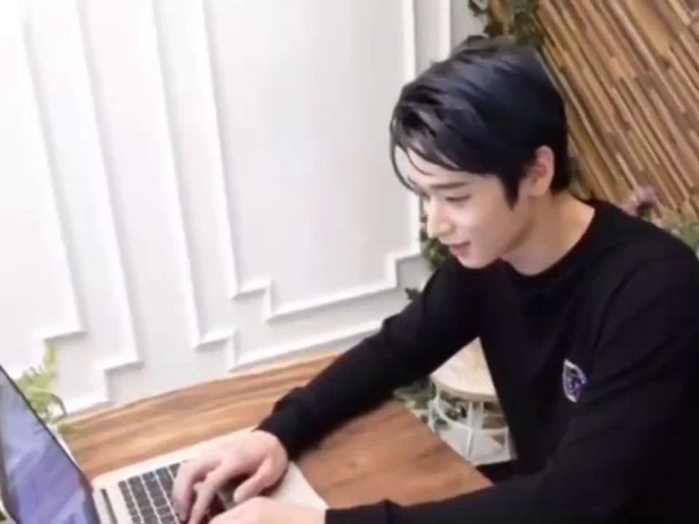 a young man is sitting at a table typing on a laptop computer .