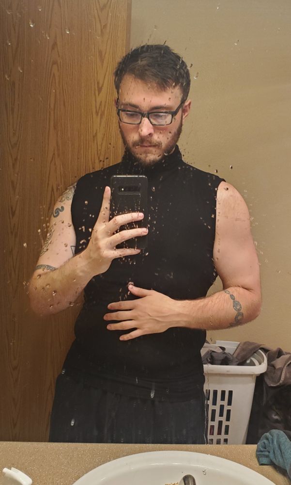 Me taking a picture of myself in a black outfit that shows off my arms. The mirror is a little damp sorryyy