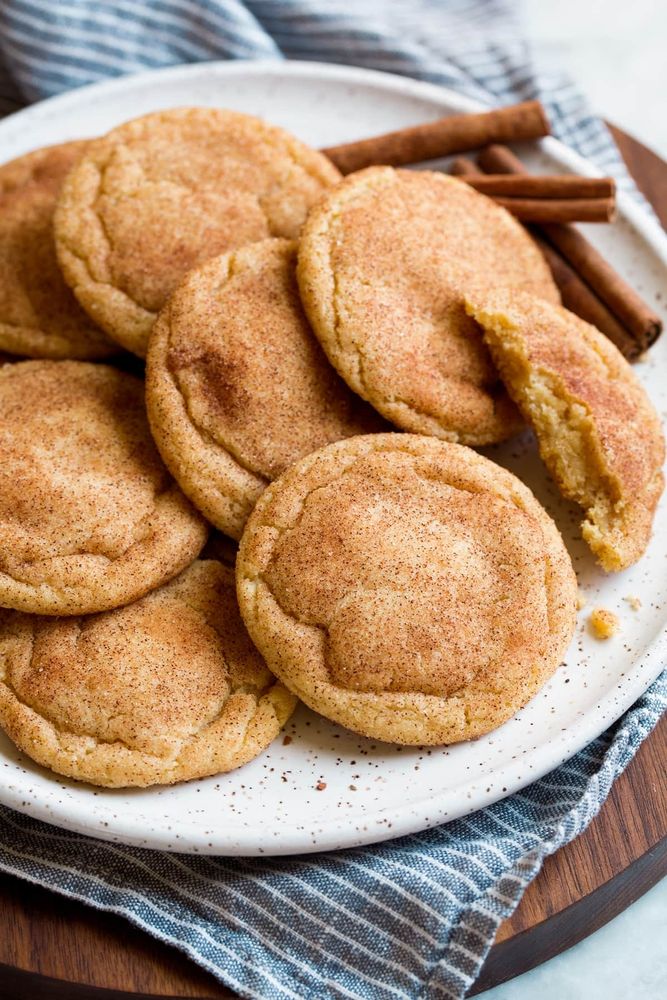 A plate of snickerdoodle cookies served with cinnamon sticks