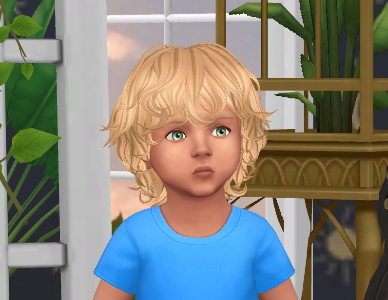 A Sims baby with messy blonde hair. He has green eyes and is wearing a blue t-shirt.