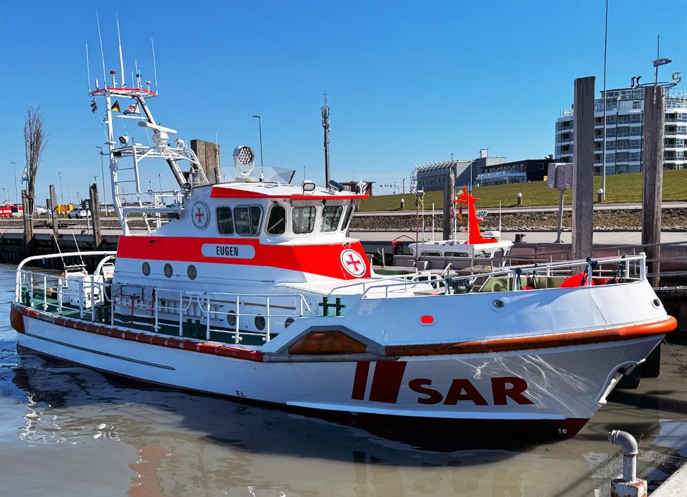 Kleiner Seenotretter mit dem Namen EUGEN liegt an sonnigem Tag im Hafen.