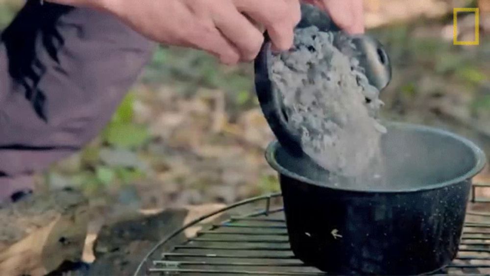 a person is pouring rice into a pot of water on a grill