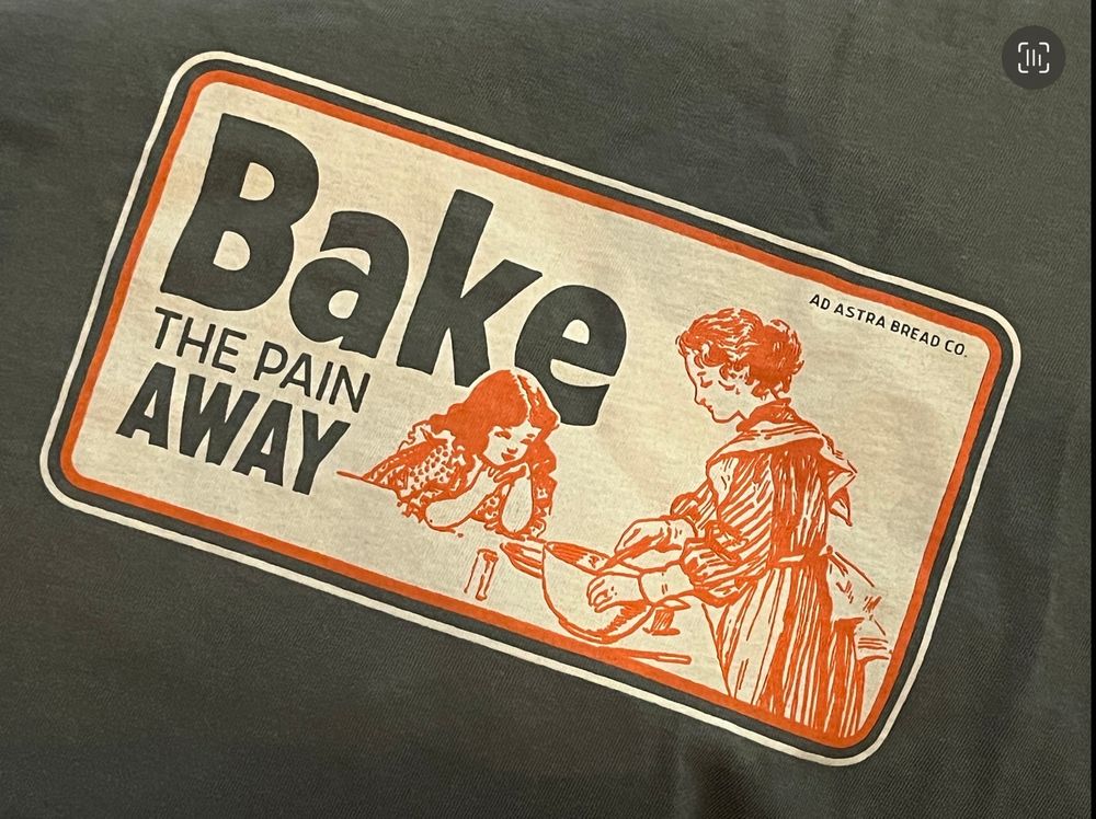 Dark green graphic tees with a woman and daughter baking and the text written “Bake the pain away”