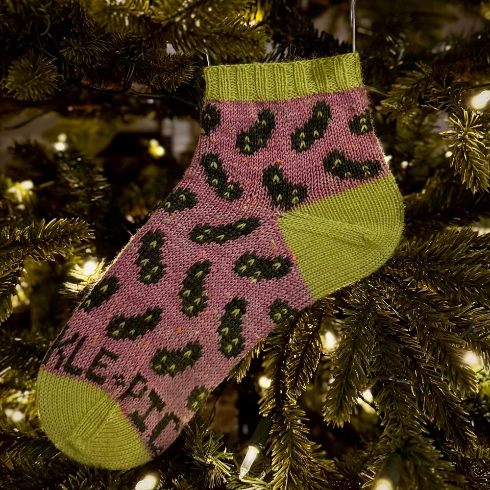 A Pickle Barrel Sock shown nestled within a warmly lit Christmas tree 