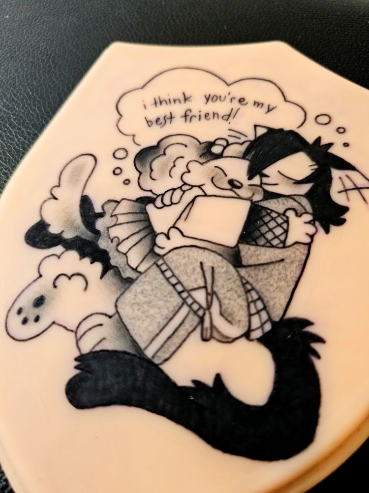 A fake skin tattoo design of an anthro dog girl hugging an anthro cat girl, with the words "I think youre my best friend!" above them.