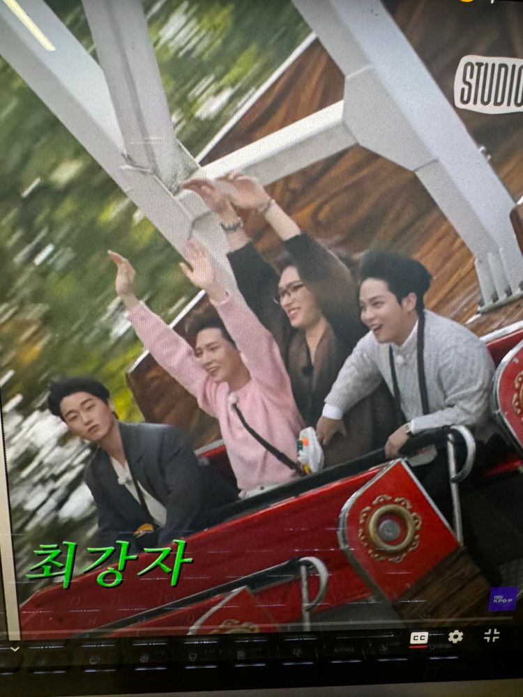 ATEEZ Jongho, Mingi, San, and Yeosang on a pirate ship ride. Mingi, Yeosang, and Jongho look to ne enjoying the ride; while San has a blank expression on his face