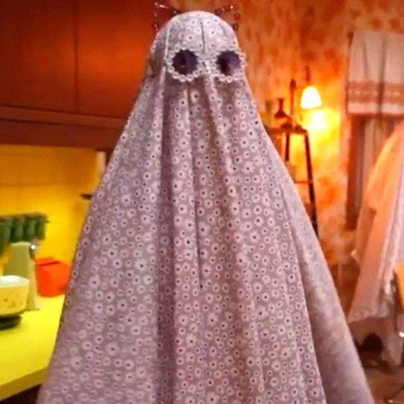 A sheet ghost costume wearing purple sheets with white flowers and wearing cat ears