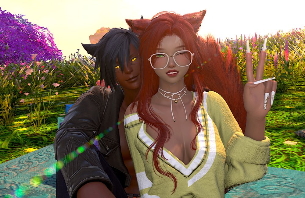 Two miqo'te, a male and a female, sit in a field on a teal blanket on a sunny day smiling and looking at the camera. She wears glasses and a loose green sweater, and he wears a black sport coat without a shirt. As she sits cuddled against him, she holds her hand up with her index and middle fingers extended as if giving a peace sign.