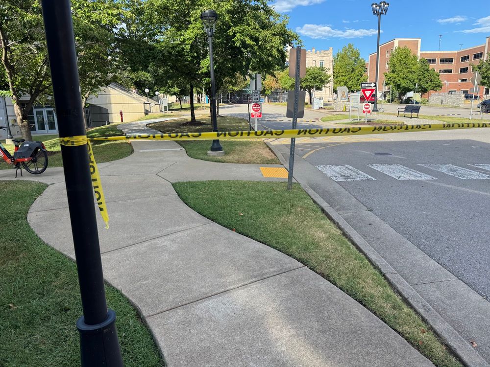 a piece of caution tape blocking the sidewalk unnecessarily 