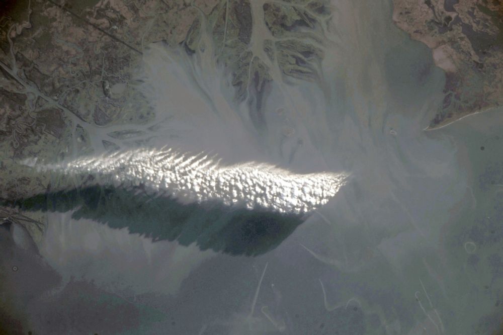 The image shows a feathery field of altocumulus clouds in the centre left part of the image. The field is casting a shadow on its lower part. At the edges of the image hazy parts of land around the bay are visible. I like these kinds of images very much, because is shows the keen eye of an astronaut spotting such a small wonder of nature.