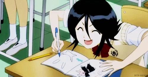 a girl is sitting at a desk writing in a notebook and smiling