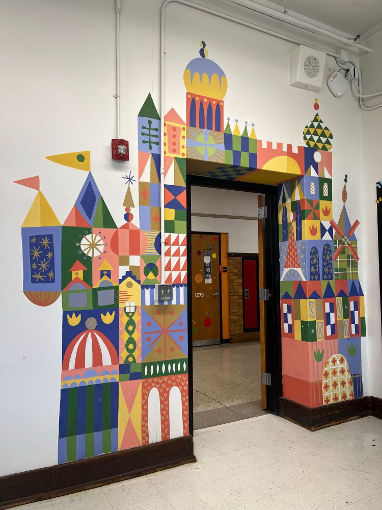 Colorful castle mural painted around a door in the style of Mary Blair 