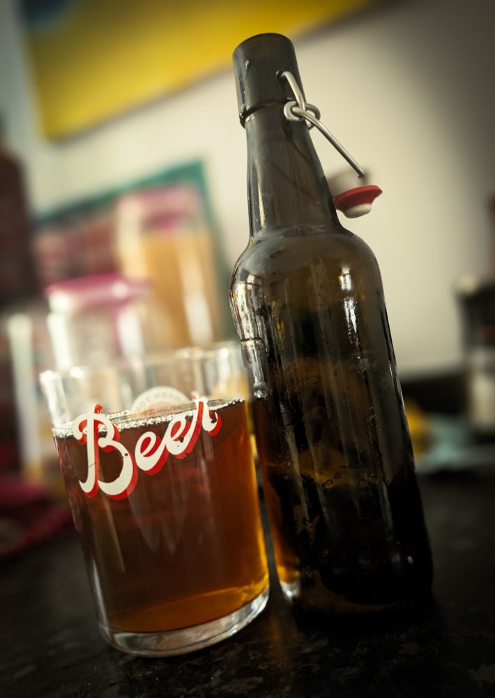 A glass of home brewed ale next to a beer bottle.