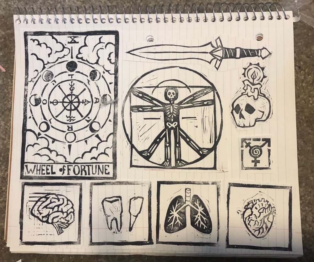 A page of stamps I carved, left to right top to bottom: the wheel of fortune tarot card, the davinci man but a skeleton, a small skull with a candle melting on top, a small trans symbol with a swirl inside, a brain, a couple teeth, a pair of lungs, and a heart